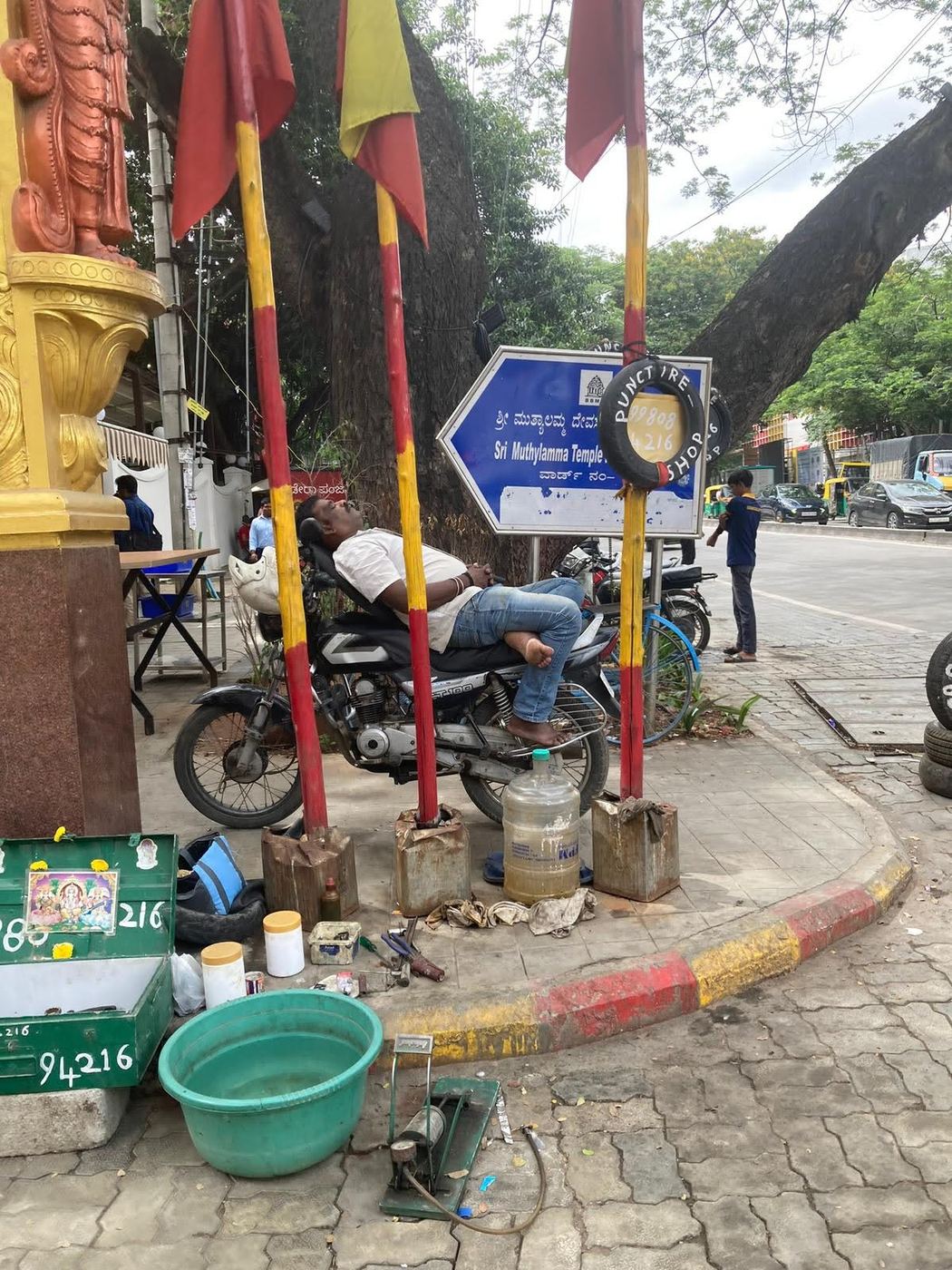 A man asleep on his parked motorbike